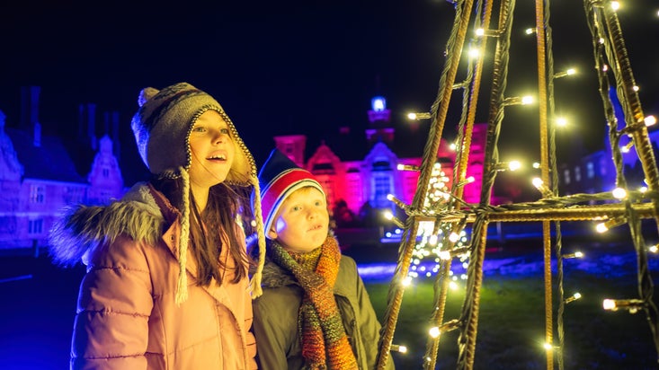 Young boy and girl look up at the Christmas lights at Blickling Estate, Norfolk